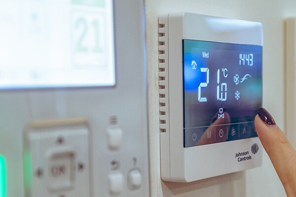Close-up of a finger tapping a Johnson Controls thermostat